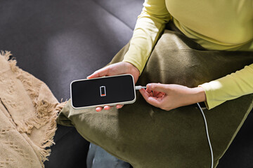 Woman hands plugging a charger in a smart phone. Charging Smartphone with Wireless Charging Pad at Home