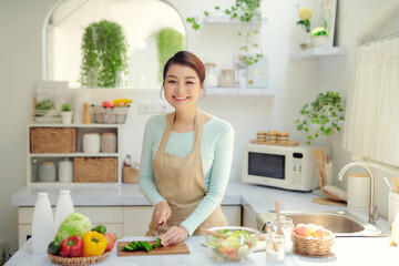 Obraz na płótnie Canvas Woman cutting fresh cucumber at table,