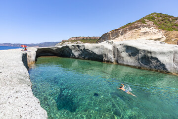 Cane Malu, a man swims in the beautiful natural pool carved into the rock on the west coast of Sardinia, Bosa, Oristano, Italy, Europe