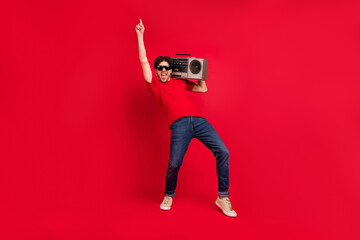 Photo of retro disco dancer guy hold boombox dance wear red t-shirt jeans shoes isolated red color background