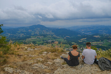 Naklejka premium couple sitting in the mountains and watching the aerial view. Hiking, camping, trekking. Couple time together