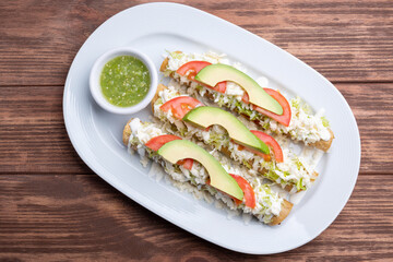 Mexican flutes, golden tacos. Traditional Mexican food. Traditional Mexican tacos with tomato, avocado and green hot sauce. Gourmet mexican food