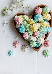 Small colorful meringues in the  wooden heartshaped bowl