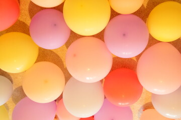 A many inflated bright yellow orange colored balloons , holiday party background