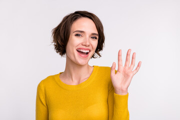 Photo of young attractive woman happy positive smile waving hand hello hi greetings isolated over...