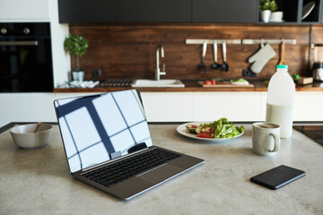 Background image of opened laptop with blank screen on kitchen counter in graphic loft design, copy space