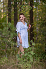 Portrait of a young beautiful blonde girl in a light dress in the park.