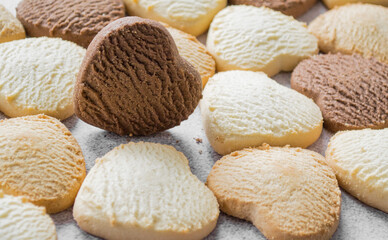 Lots of colorful heart-shaped cookies on a baking sheet, chocolate is on the edge