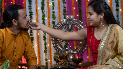 Indian families celebrating Raksha Bandhan festival a festival to celebrate the bond between brother and sister. Rakhi celebration in India. Feeding sweets, applying tikka.