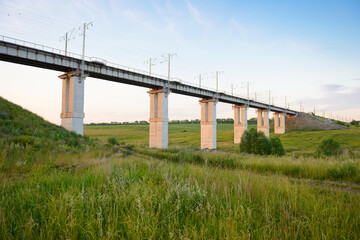 Modern railway bridge over the green ravine on a summer evening