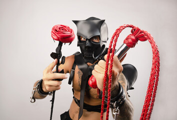 a man in bdsm wearing a skull demon mask with a whip and a rose flower, dressed in a leather...