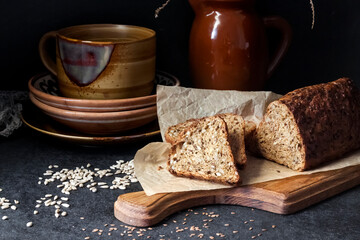 Bread with sunflower and flax seeds on a wooden cutting board on a black background