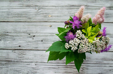 A bouquet of wild flowers on a wooden background. Rustic style. Copy space