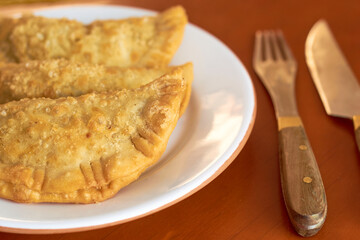 Close-up of three freshly made empanadas on your plate. Argentine gastronomy concept.