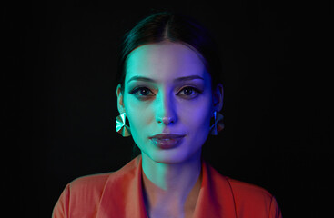 Calm confident woman portrait on dark studio background in neon light.