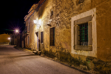 Spanish village street at night with old stone houses.