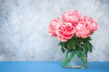 Artistic floral background. Beautiful pink peonies flowers bouquet in a glass vase. Large buds of pink peonies