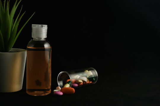 Medicine tablets and capsules come out from glass tube container with dark background