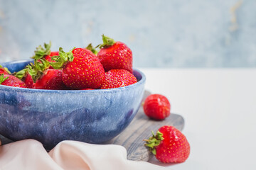 Elegant tender strawberry background. Ripe summer red berries. Filled blue bowl or plate by seasonal strawberries. Sweet berry for morning breakfast