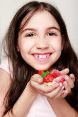 girl smiling at camera with lots of candies in her hands