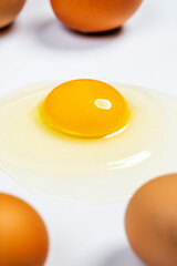 Cracked raw egg with yellow yolk and gleaming clear white on white table