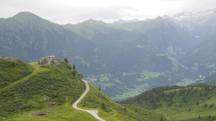 Green mountains with a house on the peak with trees