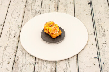 Crispy salmon nigiri with mango on slate plate