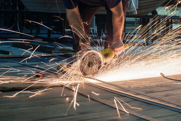 Worker working with a circular grinder on a metal with sparks flying out of them