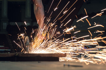 Worker working with a circular grinder on a metal with sparks flying out of them