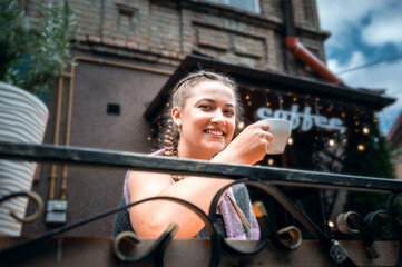 Young woman drinking coffee in a cafe on the street