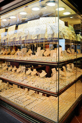 A glass showcase of a jewelry store. A lot of jewelry made of precious metals, silver and gold with gems. Shop for tourists on Ponte Vecchio. Florence, Italy.