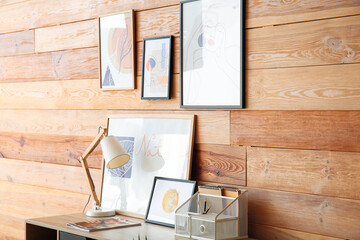 Modern workplace with stylish pictures near wooden wall