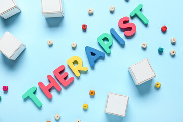 Word THERAPIST and cubes on color background