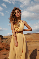 beautiful woman with blond hair in elegant dress posing in desert