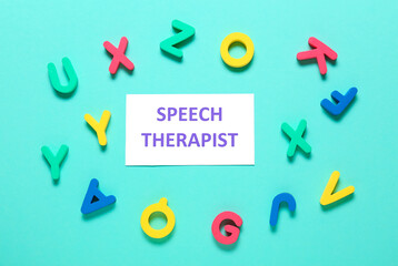 Paper with text SPEECH THERAPIST and letters on color background