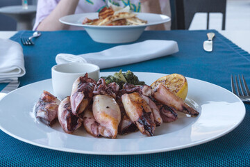 Grilled squid with potatoes and spinach on a white plate. Dish with seafood. Romantic dinner at a fish restaurant in the resort of Montenegro. Travel by Montenegro.