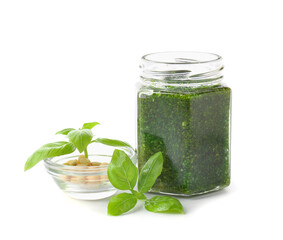 Jar with fresh pesto sauce and ingredients on white background