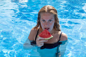 beautiful girl with piercings bathes in the pool and eats watermelon