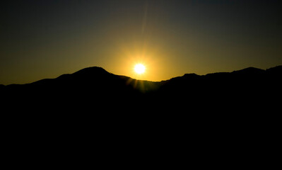 Sun setting behind the mountains at sunset