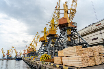 Fototapeta na wymiar Metal pipes and stacks of timber ready for shipment in sea port in Ukraine