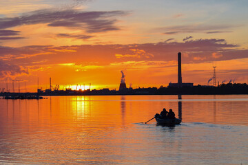 A beautiful sunset on the river, a boat with oars with a soft effect against the background of...
