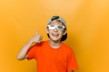 a child in a cap and glasses for watching movies shows a thumbs up and laughs merrily
