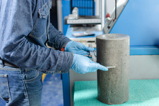 Male industrial worker's hands with blue latex gloves measuring a concrete cylinder