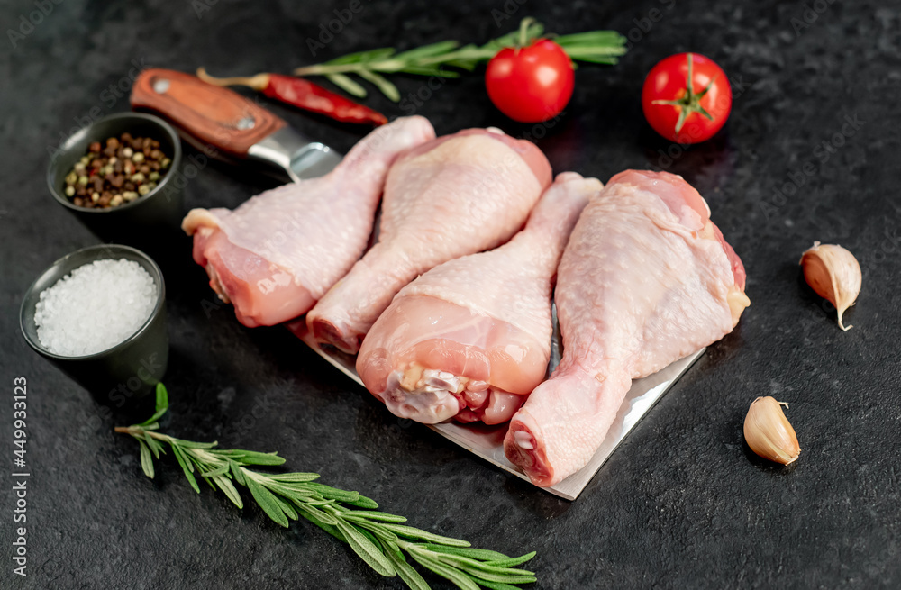 Wall mural raw chicken legs on a knife on a stone background