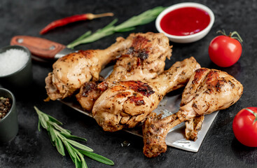 grilled chicken legs with spices on a knife on a stone background