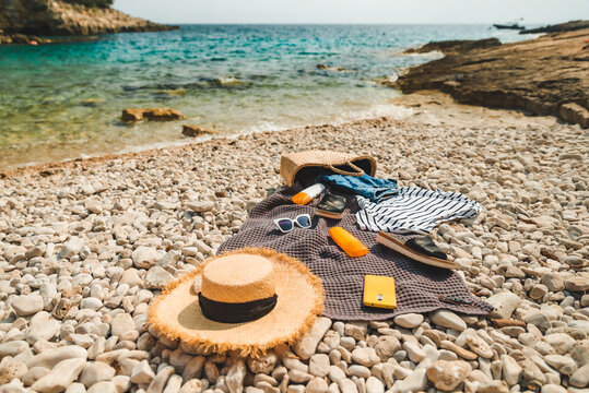 overhead view of beach stuff blanket with sun protection cream straw hat with bag