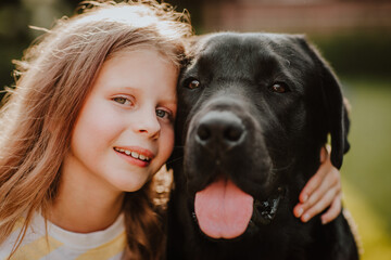 Portrait of pretty young girl and black two years old labrador retriever