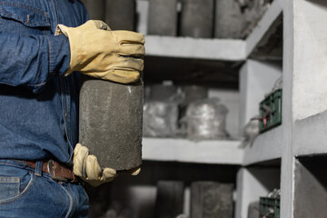 Close up of male industrial worker's hands with protective gloves holding a test concrete cylinder