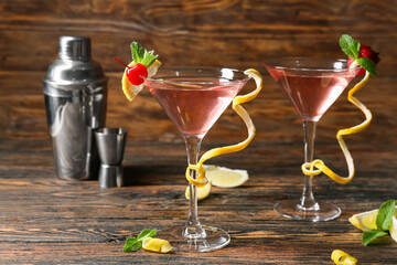Glasses of tasty cosmopolitan cocktail and shaker on wooden background