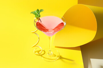 Glass of tasty cosmopolitan cocktail on color background